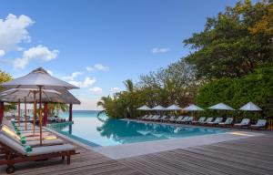 una piscina en un complejo con sillas y el océano en Adaaran Select Meedhupparu - with 24hrs Premium All Inclusive, en Meedhoo