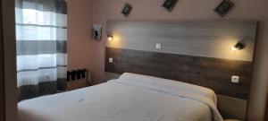 a bedroom with a white bed with a wooden headboard at Hotel du 6 juin in Sainte-Mère-Église
