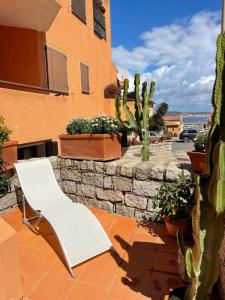 un banco blanco sentado al lado de un edificio con cactus en Casa Fiorella - Vista Mare, en Palau