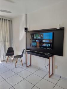einen TV an einer Wand mit einem Tisch und einem Stuhl in der Unterkunft Precioso apartamento frente al mar in Florianópolis