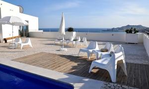 a group of white chairs sitting next to a pool at APARTAMENTO TURÍSTICO CARBONERAS in Carboneras