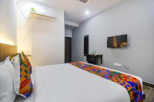 a bedroom with a white bed with a colorful blanket at FabHotel W Grand Suites in Hyderabad