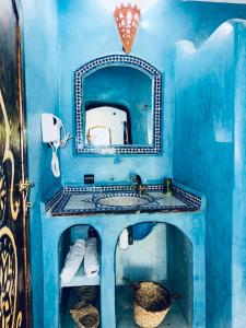 ein blaues Badezimmer mit einem Waschbecken und einem Spiegel in der Unterkunft Paradis Touareg in Zagora