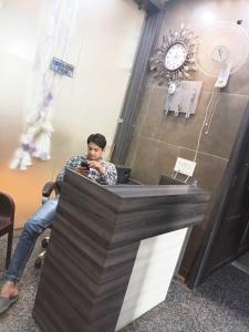 Człowiek siedzący przy ladzie patrzący na komórkę w obiekcie OYO Hotel Anjani w mieście Pānīpat