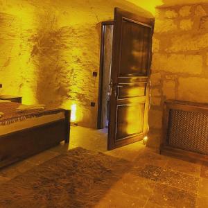 a room with a bed and a door and a fireplace at Ürgüp Inn Cave Hotel in Ürgüp