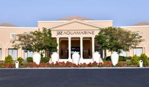 a building with trees and flowers in front of it at Jaz Aquamarine Resort in Hurghada