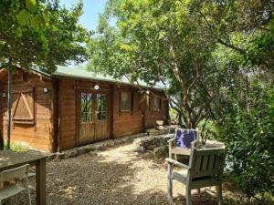 a wooden cabin with a chair in front of it at משק חפר - בקתות כפריות עם פרטיות מלאה - כולל שעה של טיול רנג'ר זוגי עצמאי in Abirim