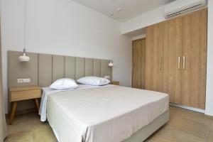 パレオコラにあるRosemary Apartmentsの白いベッドと木製キャビネット付きのベッドルーム1室が備わります。