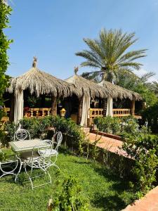 eine Hütte mit einem Tisch und Stühlen im Gras in der Unterkunft Paradis Touareg in Zagora