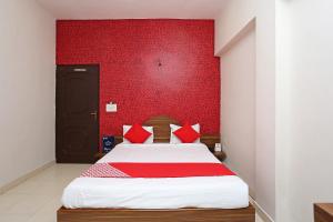 a bedroom with a bed with a red wall at Flagship Hotel Gurukripa in Raipur