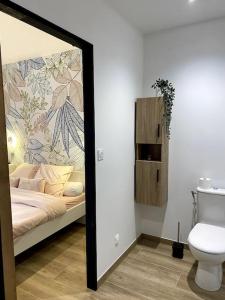 a mirror in a bathroom with a bed and a toilet at Gite du Pavillon in Rocroi