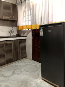 eine Küche mit einem schwarzen Kühlschrank und einer Spüle in der Unterkunft Aberdare Home in Othaya