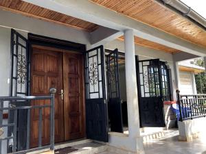 Aberdare Home في Othaya: منزل مع باب خشبي وبوابات حديد مفروشة