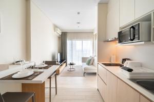 Veranda Residence/1BR/25th floor في نا جومتين: مطبخ مع دواليب بيضاء وغرفة معيشة