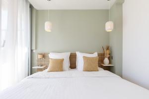 ein weißes Schlafzimmer mit einem großen weißen Bett mit Kissen in der Unterkunft XXL 2 beds with XXL terrace next to Martinez Hotel in Cannes