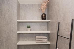 a bathroom with white shelves with towels and a vase at Huyzevier in Middelkerke +33 photos