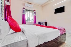 a bedroom with a large white bed with red pillows at OYO Satya Homes in Khandagiri