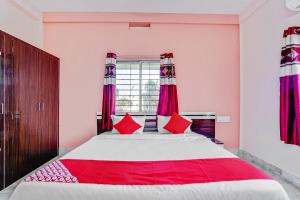 um quarto com uma cama grande e almofadas vermelhas em OYO Satya Homes em Khandagiri