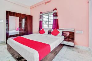 um quarto com uma cama grande e almofadas vermelhas em OYO Satya Homes em Khandagiri
