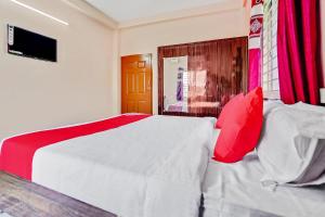 una camera da letto con un grande letto bianco con cuscini rossi di OYO Satya Homes a Khandagiri