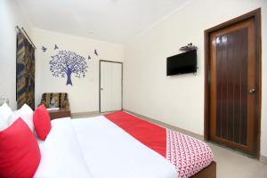 a bedroom with a bed with red pillows and a tv at Super OYO Hotel Supreme in Chandīgarh