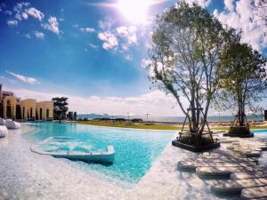 a swimming pool with a boat in the water at Veranda Residence - Beachfront 1BR Condo - High Floor in Na Jomtien