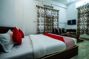 1 dormitorio con cama con almohadas y cortinas rojas en OYO Hotel Blue Lotus en Pushkar