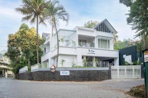 a white house with a stone wall and palm trees at The Elms Thekkady in Thekkady