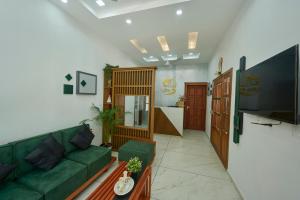 The Elms Thekkady في تيكادي: غرفة معيشة بها أريكة خضراء وتلفزيون