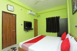 Bārang的住宿－OYO Ms Plaza，一间卧室配有一张带红色枕头的床和一台电视。