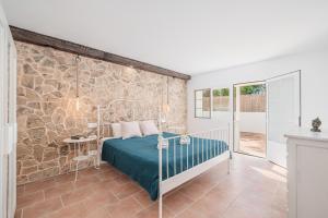 - une chambre avec un lit et un mur en pierre dans l'établissement Villa Abril, à Santanyí