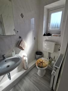a bathroom with a sink and a toilet and a window at Pension Haus Erika in Cuxhaven