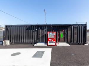 un bâtiment noir avec un panneau devant lui dans l'établissement HOTEL R9 The Yard Koge, à Nakatsu