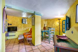 uma sala de estar com paredes amarelas e uma mesa e cadeiras em El Nido holiday cottage with pool em Órgiva