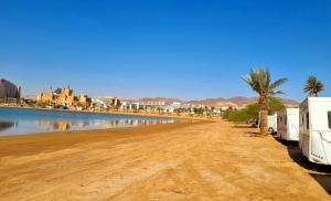 uma estrada de terra ao lado de um rio com uma caravana estacionada em קרוואן על החוף em Eilat