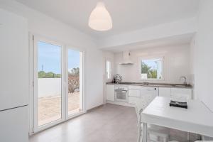 Una cocina blanca con una mesa y sillas blancas. en Es Raco Sa Rapita, en Llucmajor