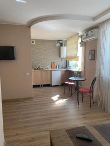 ein Wohnzimmer mit einem Tisch und Stühlen sowie eine Küche in der Unterkunft Апартаменты на пр Гагарина in Dnipro