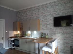 a kitchen with white cabinets and a brick wall at On Yer Bike & Gone Fishin in Millport