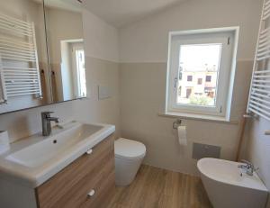 uma casa de banho com um lavatório, um WC e uma janela. em Da.Ma. House em Anzio