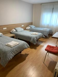 three beds in a room with wooden floors at Pension Valcarce in Ponferrada +40 photos