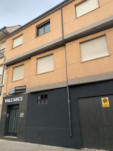 a building with a garage and a sign that reads valence at Pension Valcarce in Ponferrada