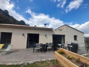 a patio with a table and chairs and a house at VILLA Adrien , maison de charme. in Casanova