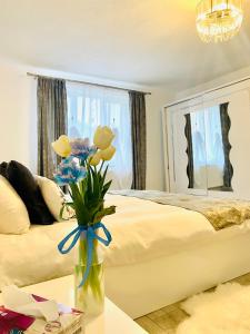 um quarto com uma cama e um vaso com flores sobre uma mesa em Central House em Sighisoara