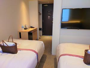 a hotel room with two beds and a flat screen tv at Tosei Hotel Cocone Kamakura in Kamakura