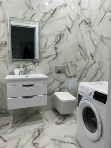 a white bathroom with a washing machine and a sink at Уютная квартира вблизи Байтерека in Astana