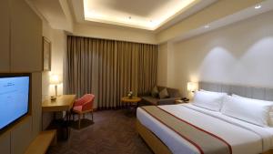 Habitación de hotel con cama y TV de pantalla plana. en Orana Aurnum en Nueva Delhi