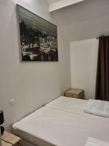 - une chambre dotée d'un lit blanc avec une photo sur le mur dans l'établissement Au beau séjour, à Mayet-de-Montagne