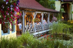 a group of people sitting on a porch next to a pond at Mirbeau Inn & Spa - Skaneateles in Skaneateles