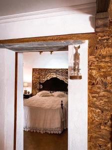 a bedroom with a bed and a stone wall at Monte da Parreira in Cabeça de Carneiro