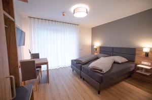 Schlafzimmer mit einem Bett, einem Tisch und einem Schreibtisch in der Unterkunft Boardinghouse Lingen in Lingen